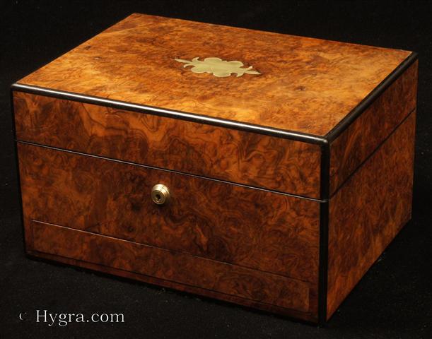 Antique ebony edged  box in highly figured burr walnut having a Bramah type lock and  a sprung drawer of dovetail construction fitted for jewelry and a lift out tray. The drawer is held in place by a brass pin driven through the facing. In the top section there is a lift-out compartmentalized tray. In the lid there is a document wallet. Circa 1860.  Enlarge Picture